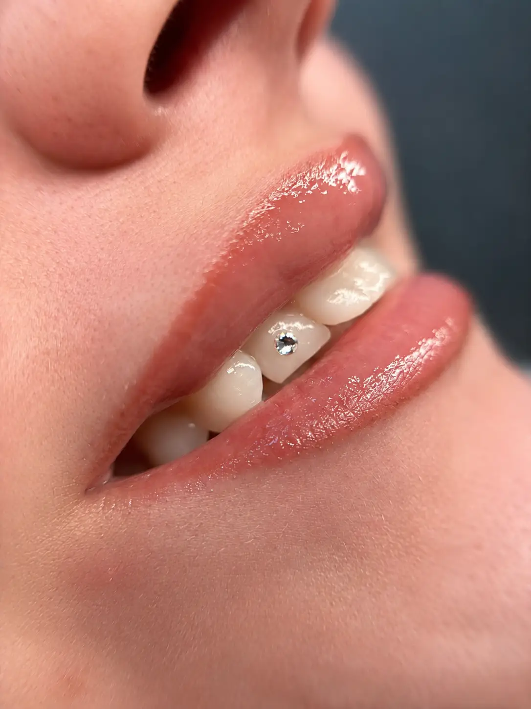 Tooth gem tandsmykke med én sten på fortand vist fra siden med naturligt smil og blanke læber.