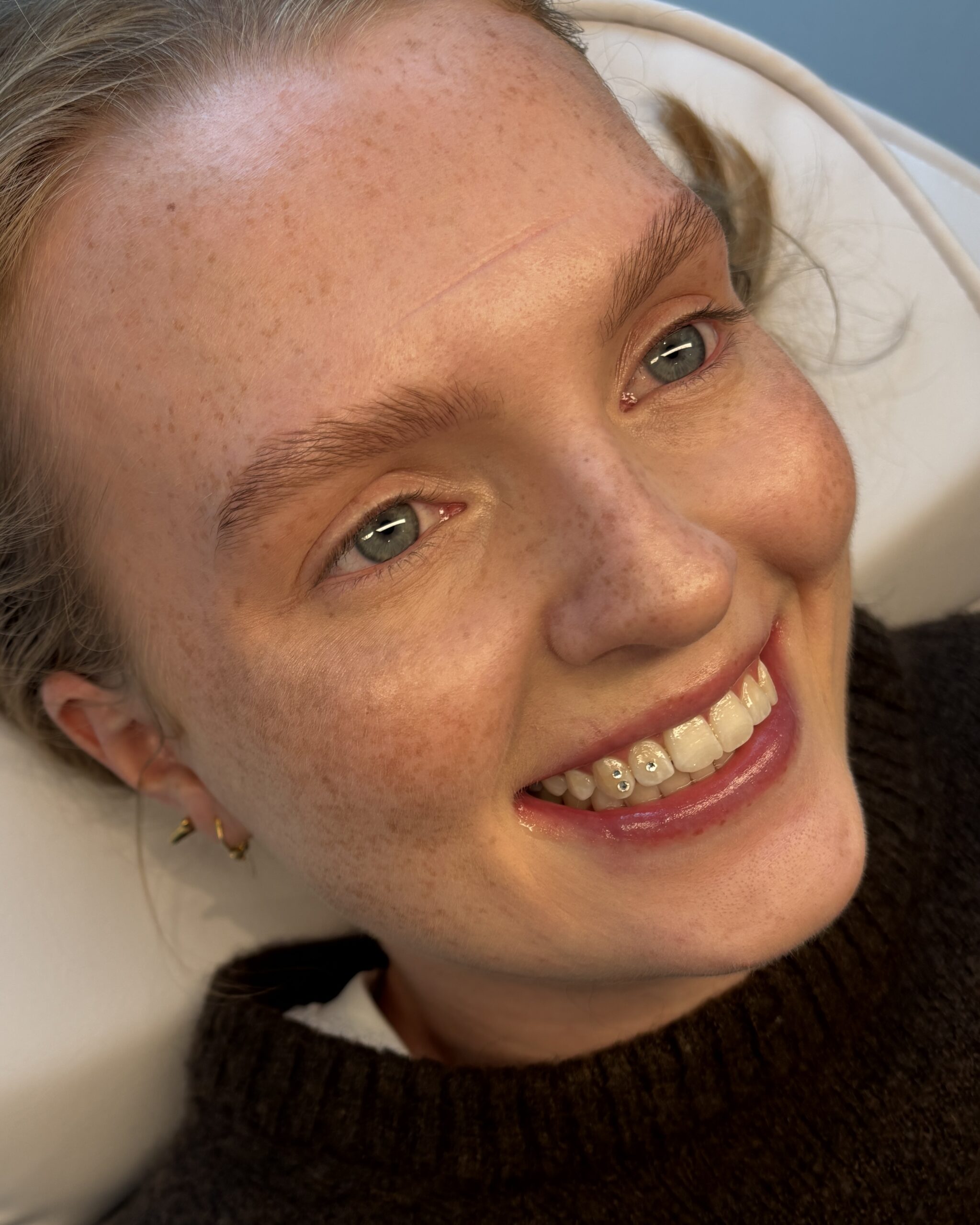 Close-up af tandsmykke design med tre klare krystaller fordelt på to tænder hos Brows & Beauty Aarhus